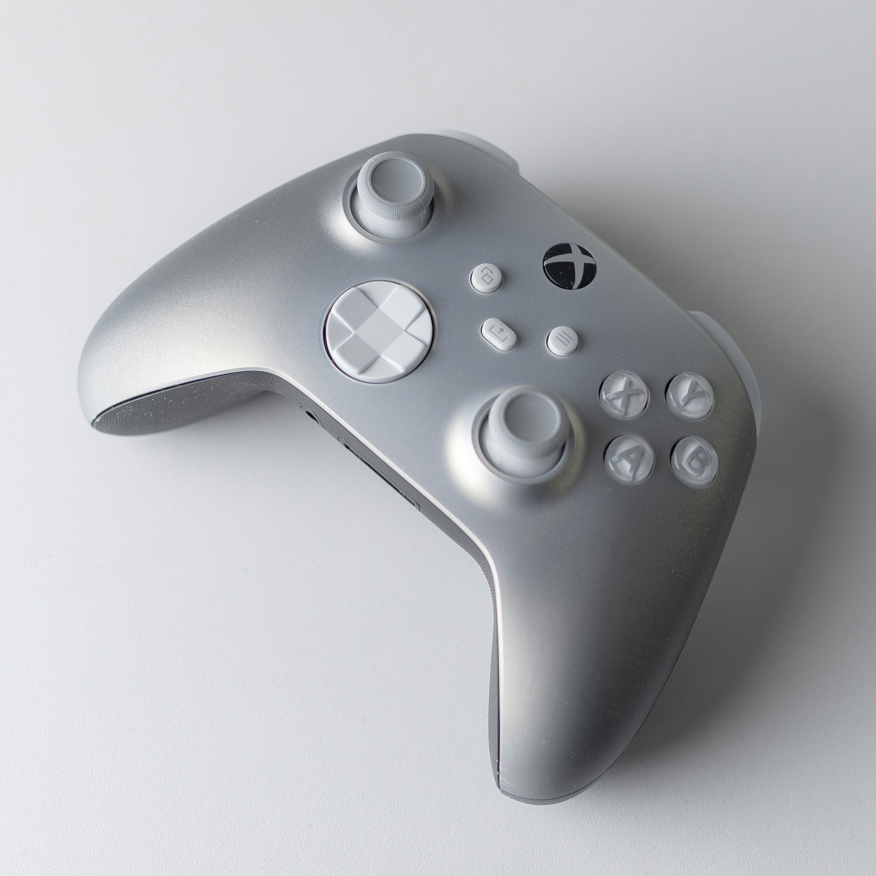 Minimalist silver Xbox controller positioned on a white surface, highlighting modern gaming technology.
